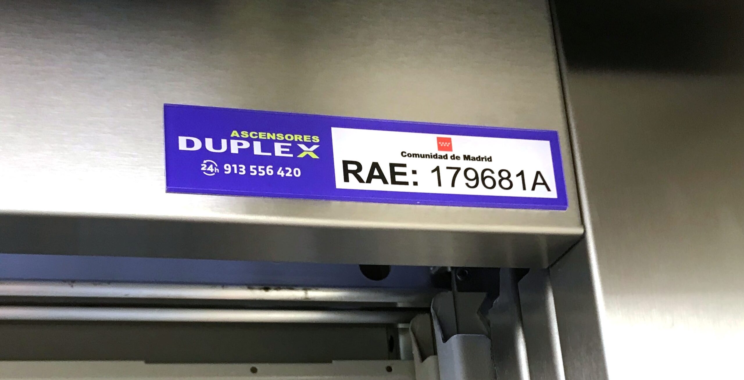 Ejemplo de placa con el número RAE del ascensor situada sobre el dintel de la cabina