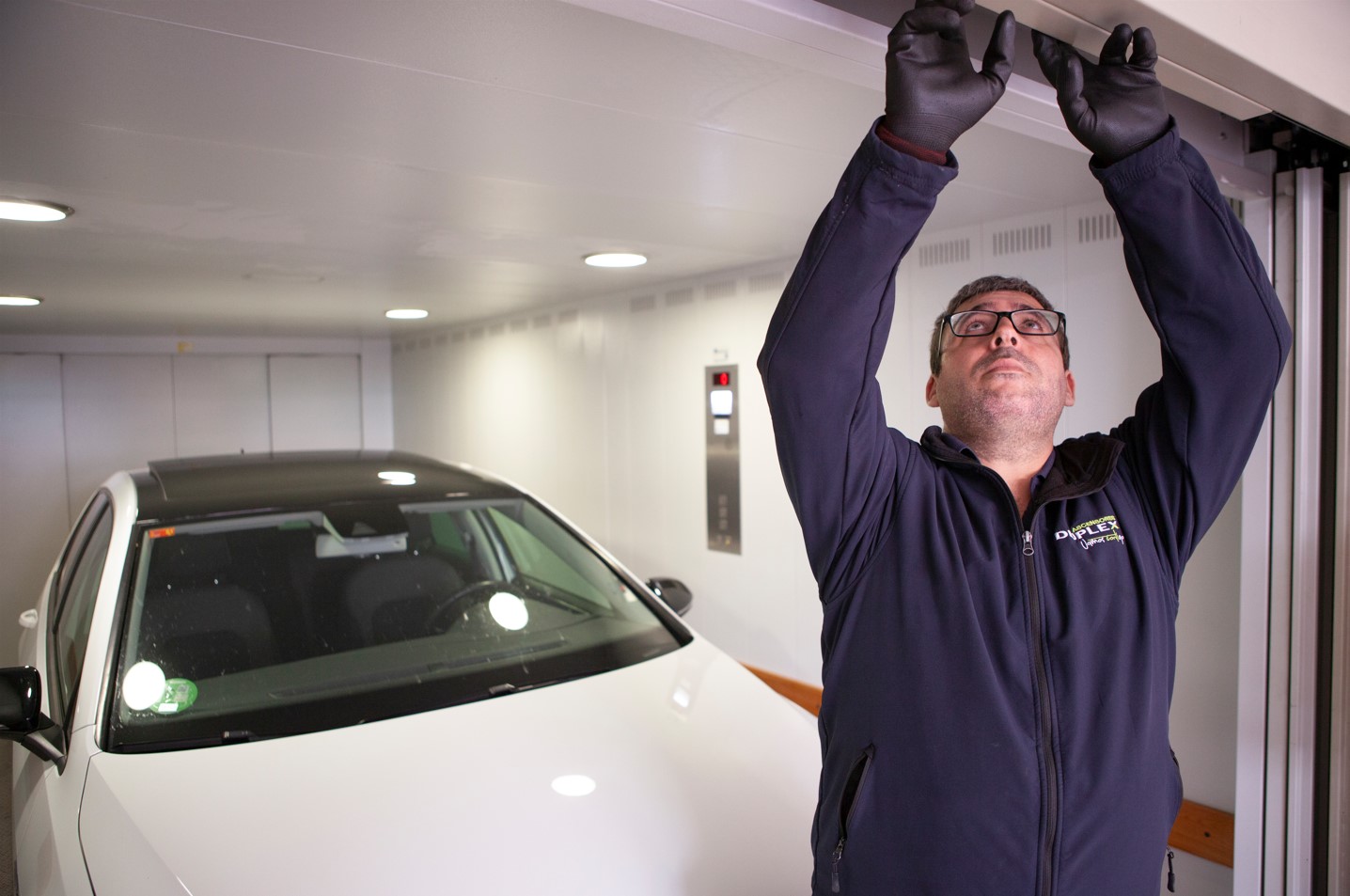 Técnico de Duplex Ascensores revisando el funcionamiento de la puerta de un garaje para cumplir la normativa vigente