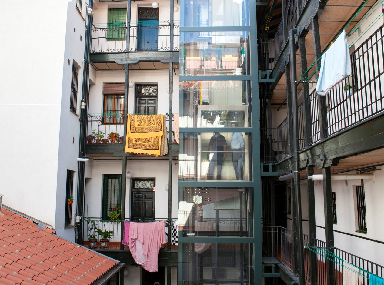 Dos hombres suben en un ascensor instalado en el patio de una comunidad de vecinos