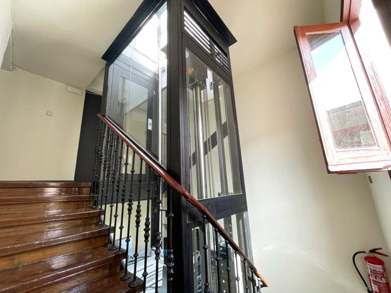 Ascensor acristalado instalado junto a las escaleras de un edificio residencial